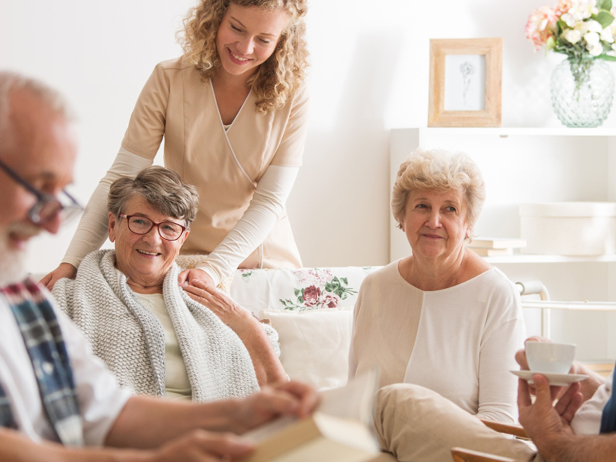 Group of senior friends sitting together at nursing home living area.