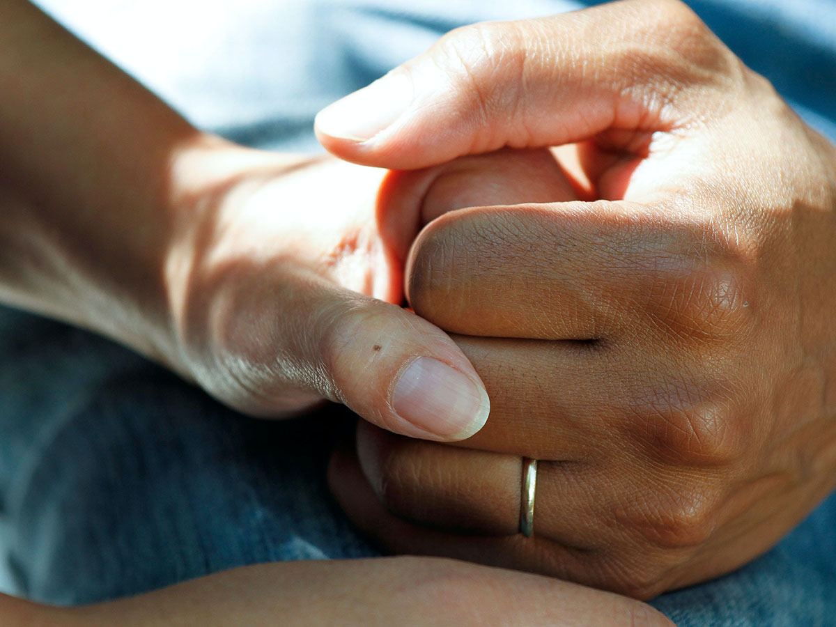 Close up of two people holding hands while one seems to be in a medical bed