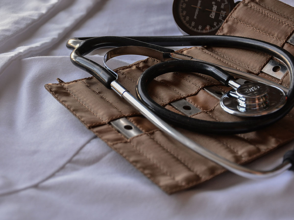 Stethoscope and other utensils in a leather case sitting on white sheets