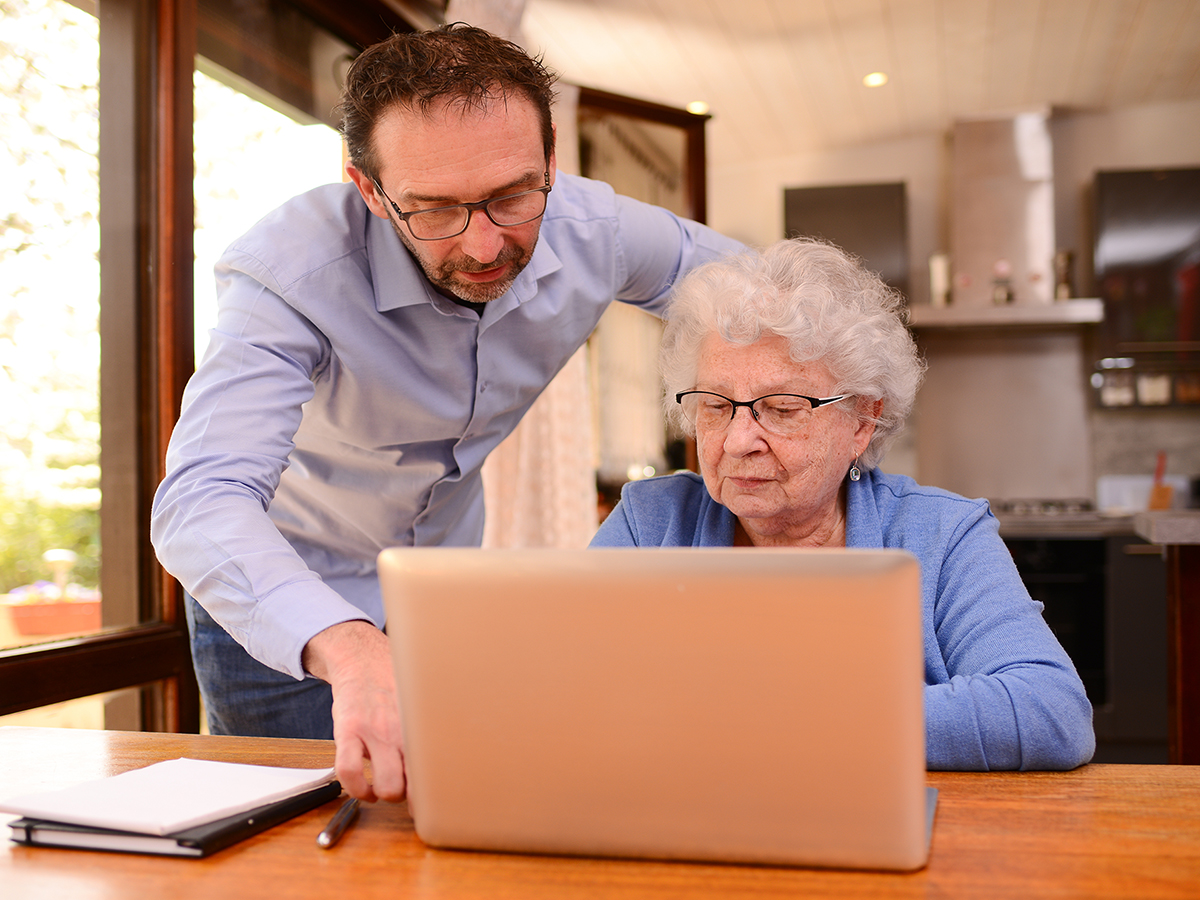 Image of a man helping an elderly woman us a computer