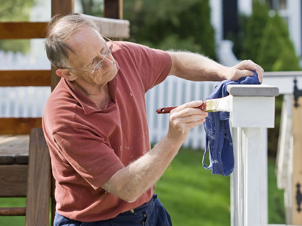 elderly man painting decking