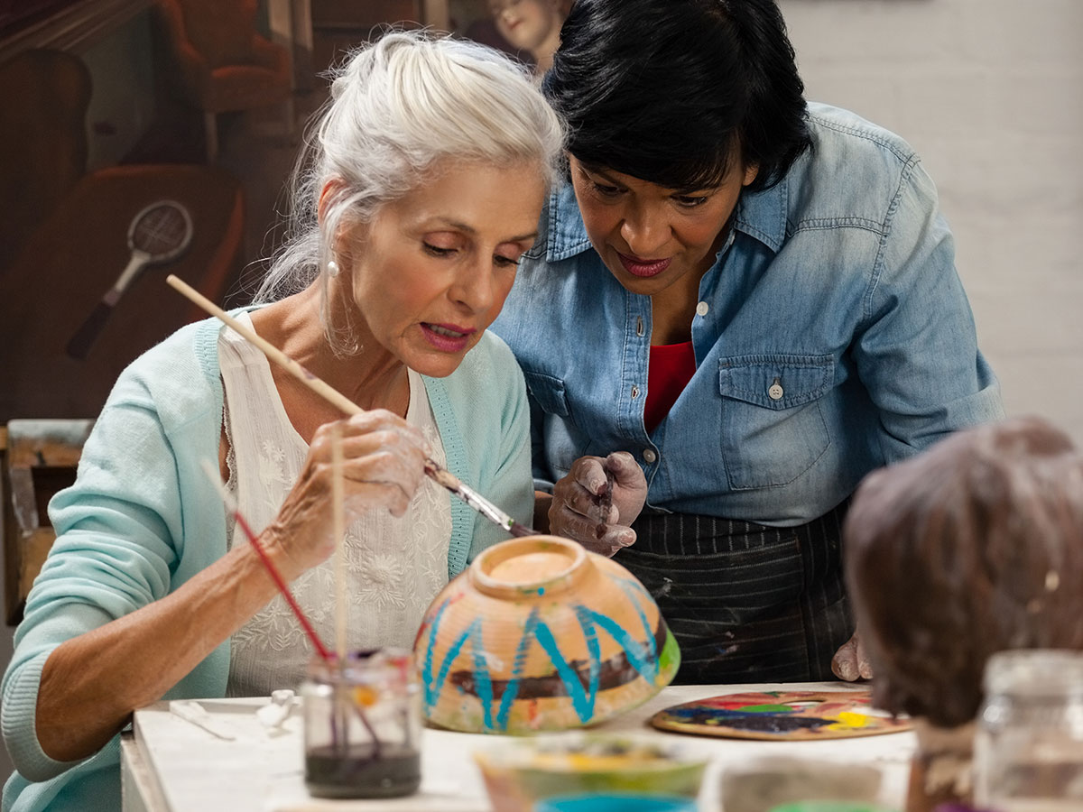 elderly woman painting pottery